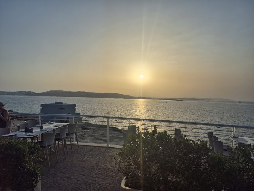 Sun going down over the sea seen past the terrace railing
