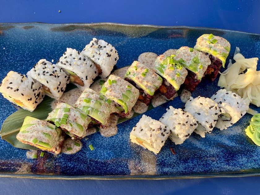 Close view of sushi rolls topped with sesame on a blue plate