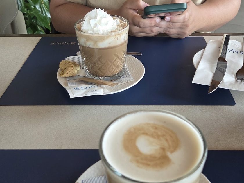 Iced coffee topped with cream beside a cappuccino