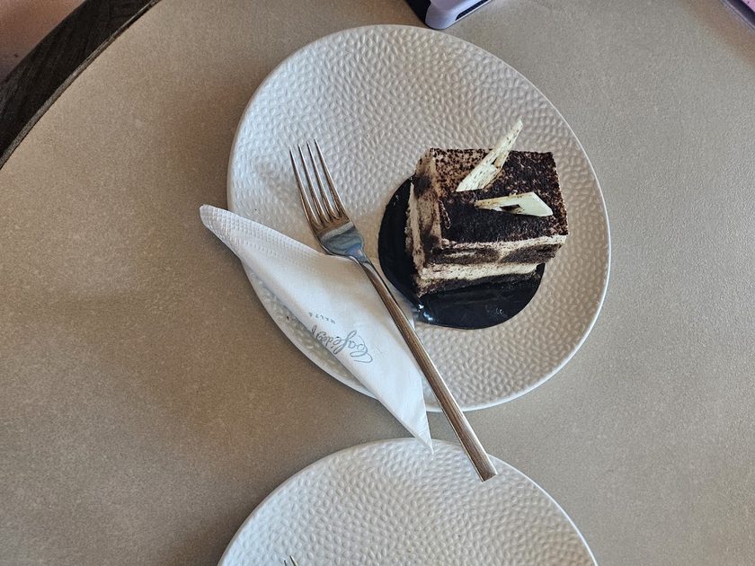 Slice of chocolate dessert on a ridged plate with a fork