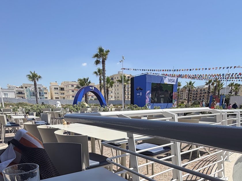 Terrace and blue archways on the promenade with palm trees behind