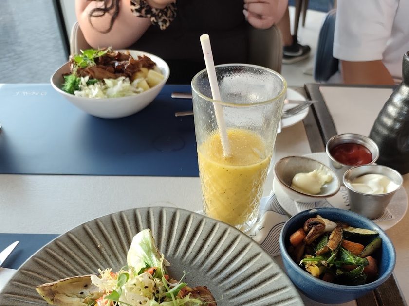 Two poke bowls with fresh orange juice on a blue table